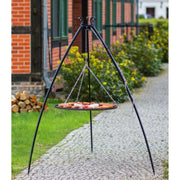 Grillstativ 200 cm med hängande grillgaller i naturligt stål – grillning i trädgårdsmiljö med tegelhus i bakgrunden