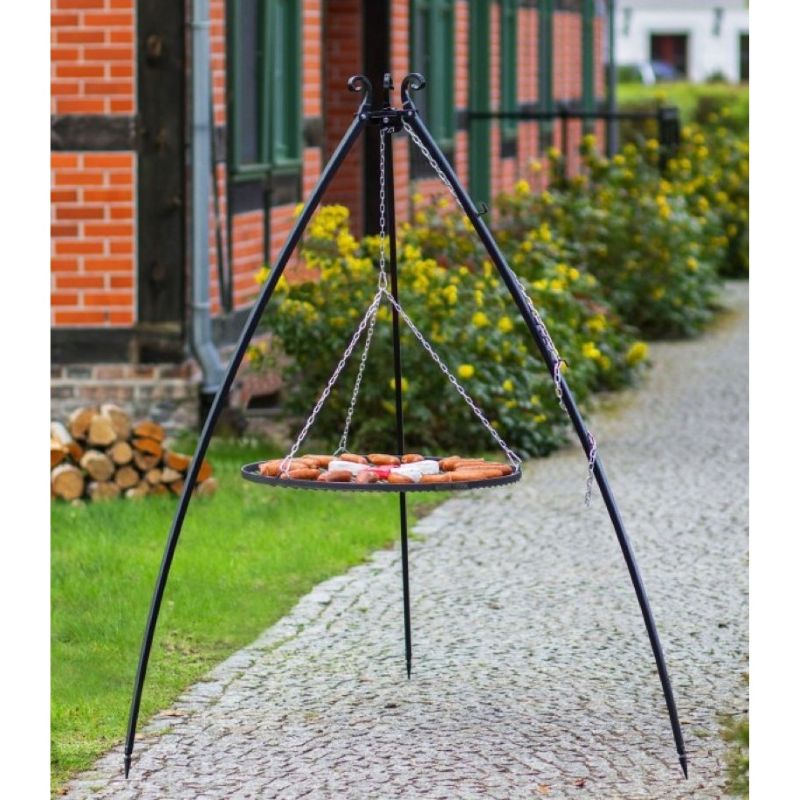 Grillstativ 200 cm med hängande grillgaller i naturligt stål – grillning i trädgårdsmiljö med tegelhus i bakgrunden