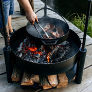 Pannan används för att grilla kött direkt över glödande kol i ett Montana X eldfat.