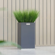 Fyrkantig stålkruka från Coyotto placerad utomhus med dekorativ växt