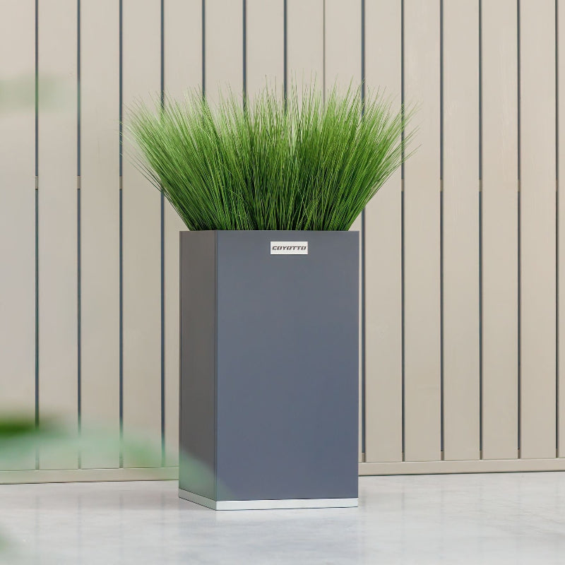 Fyrkantig stålkruka från Coyotto placerad utomhus med dekorativ växt