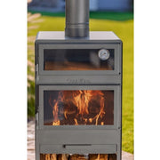 Trädgårdskamin bredvid vedförvaring i solig miljö.