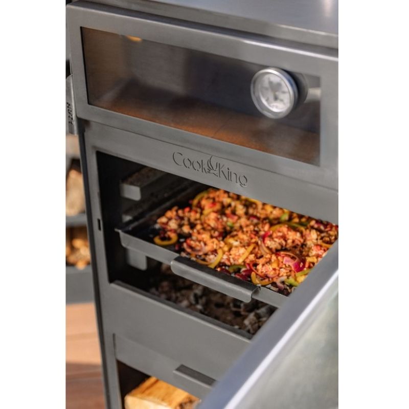 Trädgårdskamin i användning med kock i bakgrunden som förbereder mat.