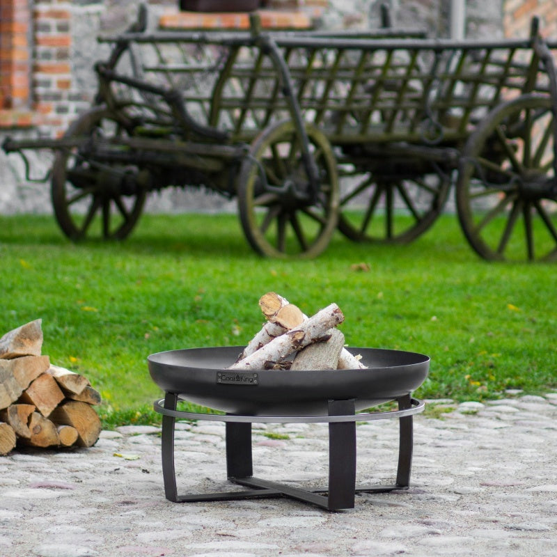 Eldfat VIKING från Cook King på stenlagd gård, omgiven av gräs och gamla vagnar.