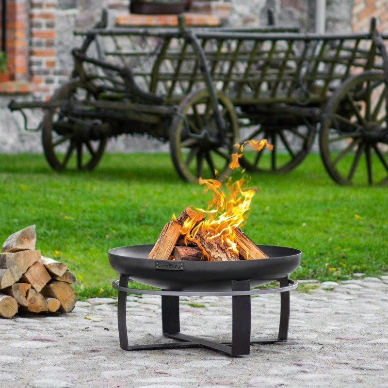 Brinnande eld i eldfat VIKING från Cook King på stenlagd uteplats.