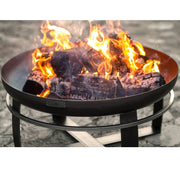 Eldfat VIKING från Cook King i en grönskande trädgård, fylld med ved och brasa.